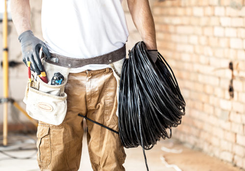 Electrician with tools, working on a construction site. Repair and handyman concept. House and house reconstruction.